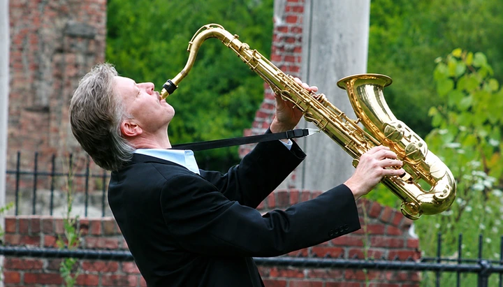 David Maxx performing outdoors with his tenor saxophone